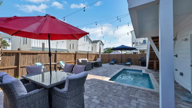 a view of a patio with couches table and chairs under an umbrella
