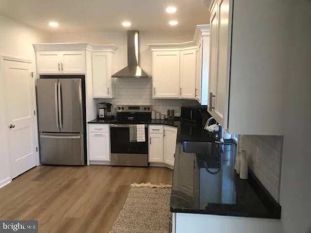 a kitchen with stainless steel appliances granite countertop a refrigerator a sink and a stove