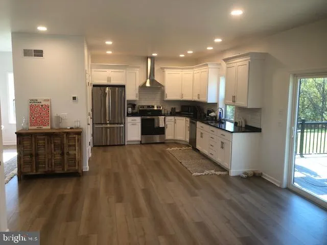 a kitchen with stainless steel appliances kitchen island granite countertop a stove a refrigerator a sink and a oven with wooden floor