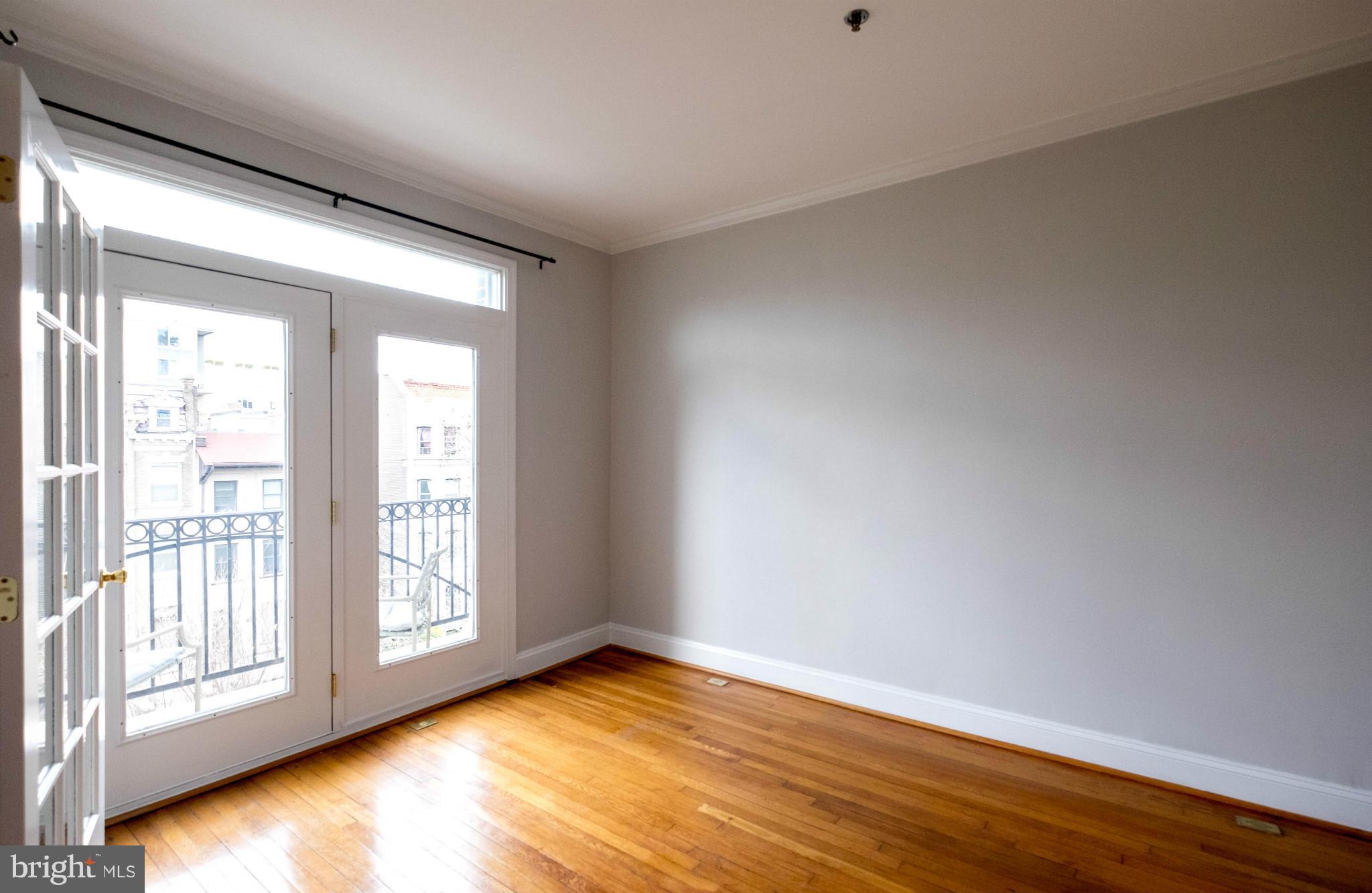 1438 Columbia Road Northwest, Unit 401 Washington, DC 20009 - Photo 4 of 10 a view of an empty room with wooden floor and a window