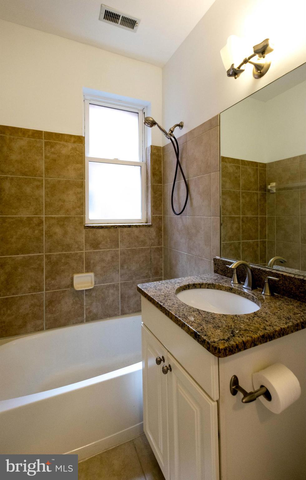 1438 Columbia Road Northwest, Unit 401 Washington, DC 20009 - Photo 6 of 10 a bathroom with a granite countertop sink a mirror and a bathtub