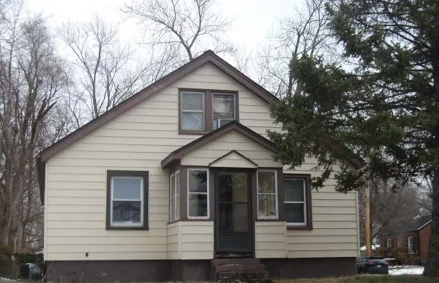 a front view of a house with yard and trees in the background