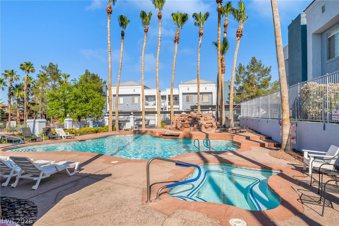 2201 Ramsgate Drive, Unit 811 Henderson, NV 89074 - Photo 2 of 36 An inviting community pool and spa area, featuring a rock waterfall and towering palm trees.