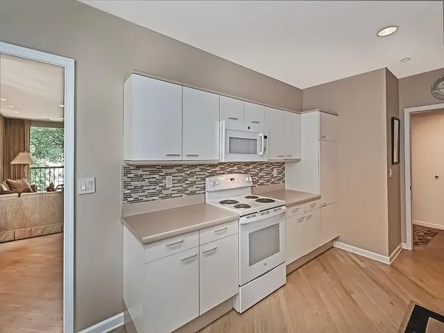 a white kitchen with a table chairs and a refrigerator