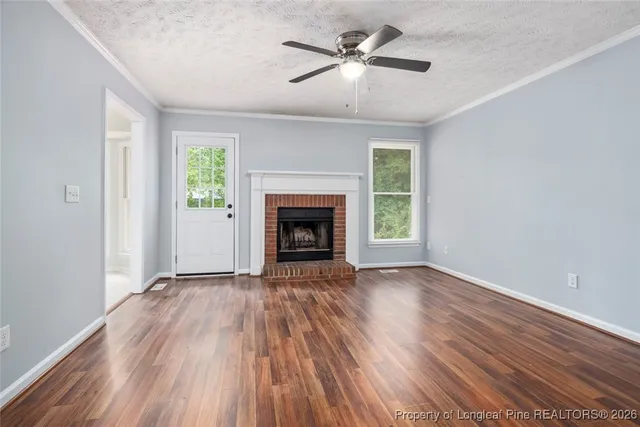 an empty room with wooden floor windows and a ceiling fan