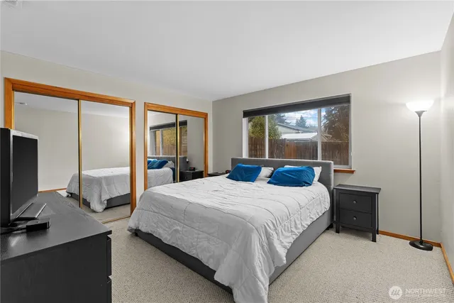 a bedroom with a bed and large windows