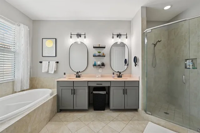 a spacious bathroom with a double vanity sink mirror and bathtub