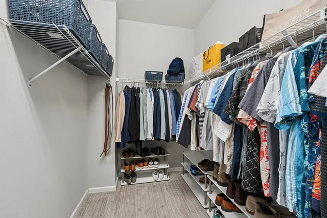 a view of walk in closet with clothes and shoes