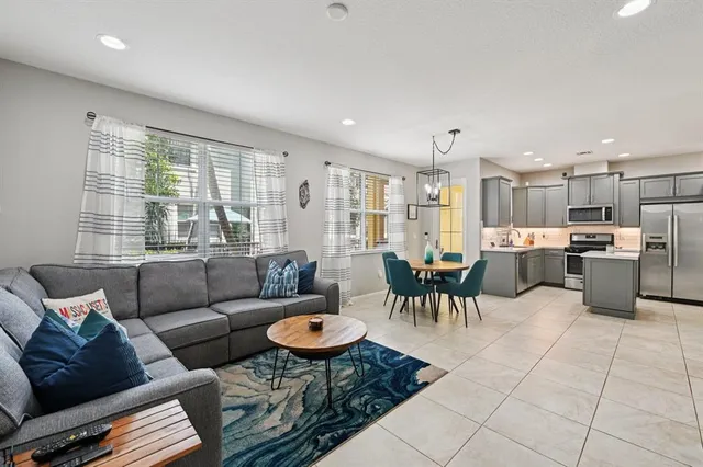 a living room with furniture kitchen view and a large window