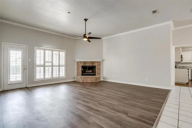 an empty room with wooden floor fireplace and windows