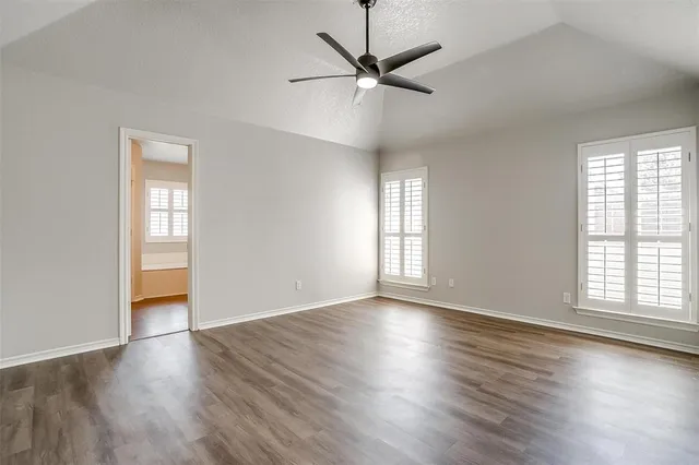 an empty room with wooden floor window and ceiling fan