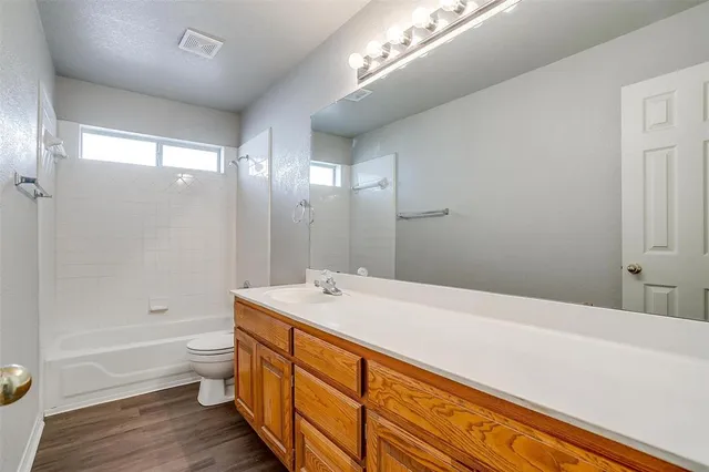 a spacious bathroom with a double vanity sink toilet mirror and bathtub