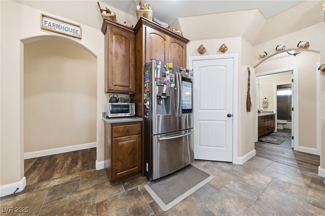 1285 Embry Avenue Moapa, NV 89025 - Photo 36 of 98 Kitchen with arched walkways, stainless steel fridge with ice dispenser, stone tile flooring, and dark brown cabinetry