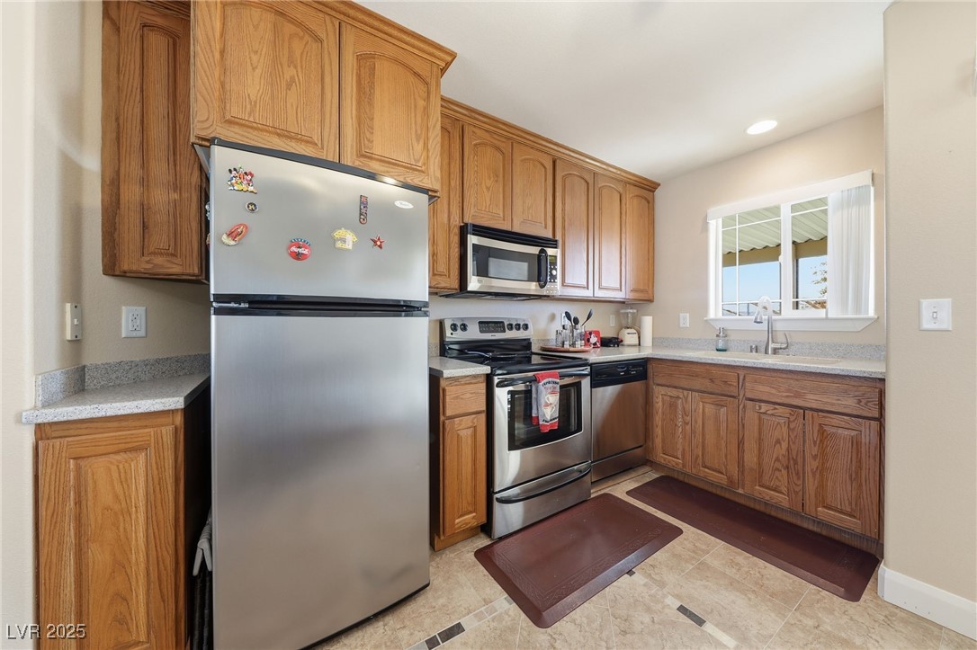 1285 Embry Avenue Moapa, NV 89025 - Photo 61 of 98 Kitchen featuring appliances with stainless steel finishes, brown cabinetry, recessed lighting, and light stone counters