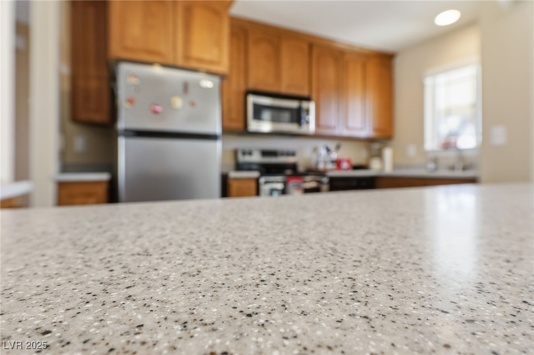 1285 Embry Avenue Moapa, NV 89025 - Photo 64 of 98 Kitchen featuring appliances with stainless steel finishes, brown cabinetry, and light stone countertops