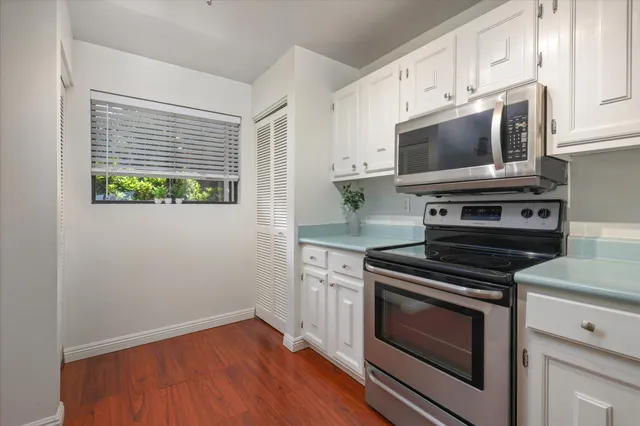 a kitchen with white cabinets stainless steel appliances and wooden floor