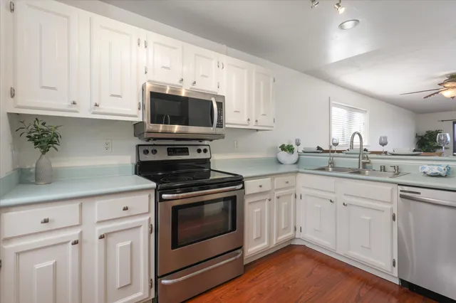 a kitchen with cabinets stainless steel appliances a sink and wooden floor