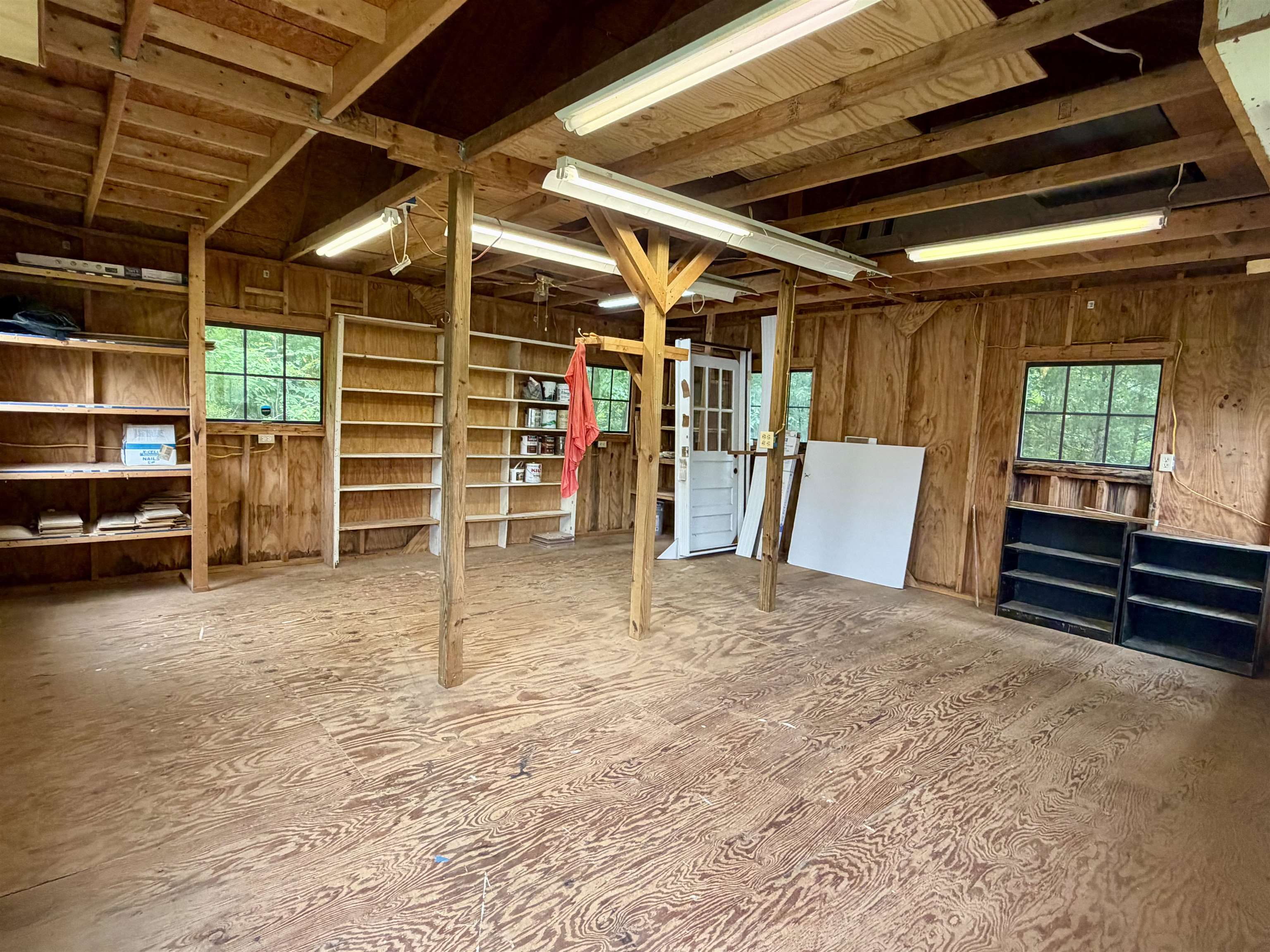 206 Burns Road Ramer, TN 38367 - Photo 31 of 37 Spacious interior featuring exposed wooden beams, built-in shelving, windows providing natural light, and fluorescent lighting fixtures