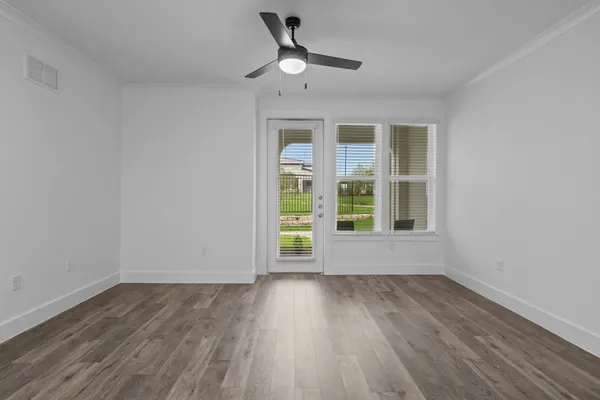 a view of an empty room with wooden floor and a window