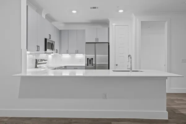 a large white kitchen with kitchen island a sink stainless steel appliances and cabinets