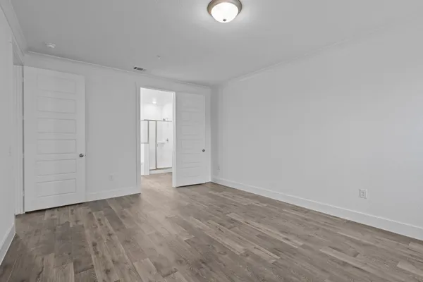 a view of an empty room with wooden floor and closet area