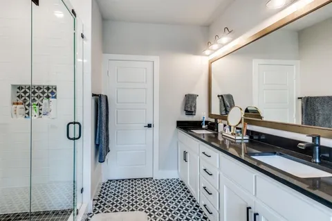 a spacious bathroom with a double vanity sink a mirror a shower and a mirror
