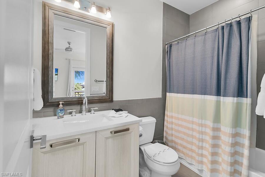 255 Columbus Way Marco Island, FL 34145 - Photo 40 of 50 a bathroom with a sink a toilet a mirror and shower curtain