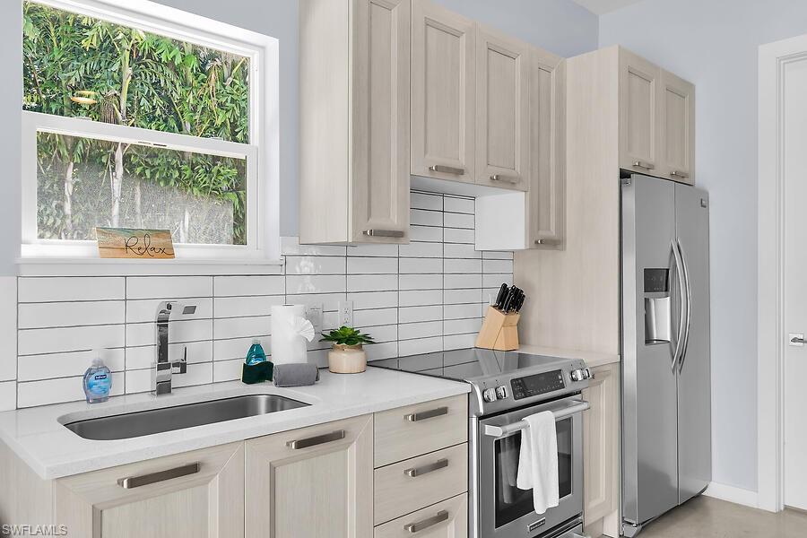 255 Columbus Way Marco Island, FL 34145 - Photo 45 of 50 a kitchen with stainless steel appliances a sink a stove and white cabinets next to a window