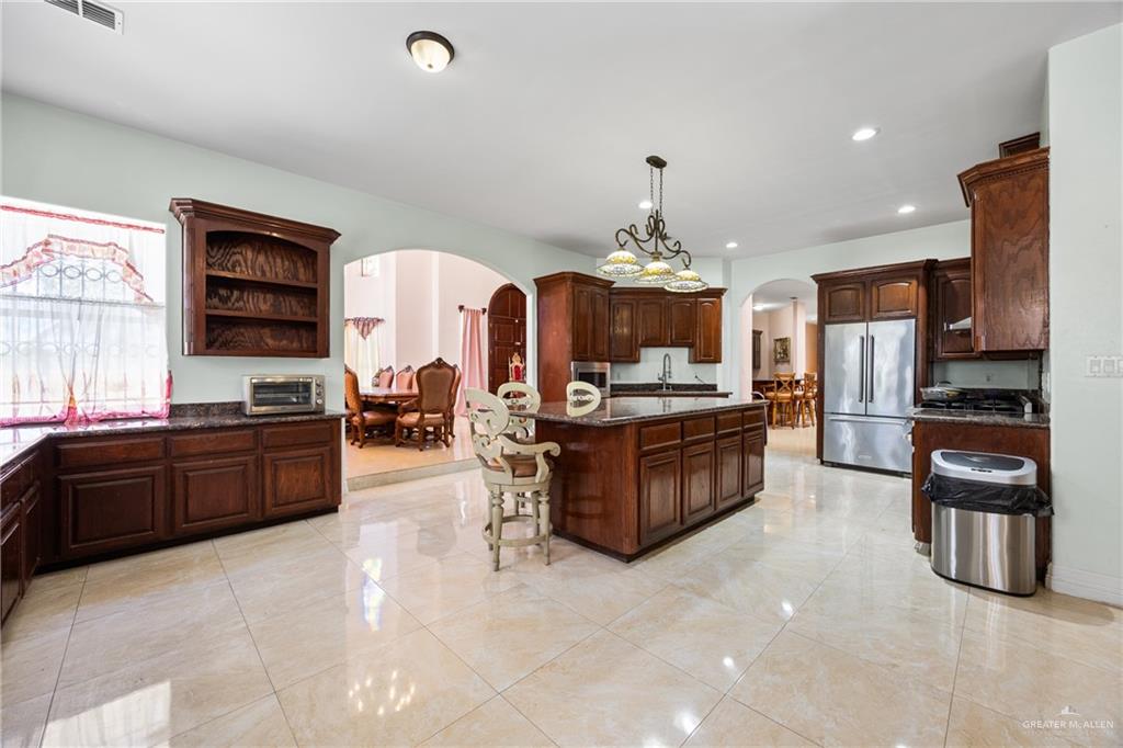 508 El Paisano Road Rio Grande City, TX 78582 - Photo 9 of 42 a kitchen with stainless steel appliances kitchen island granite countertop a stove and cabinets