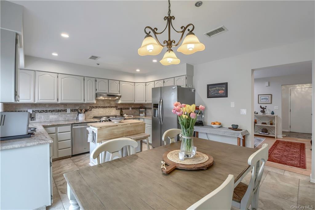 a kitchen with stainless steel appliances kitchen island granite countertop wooden cabinets and chandelier