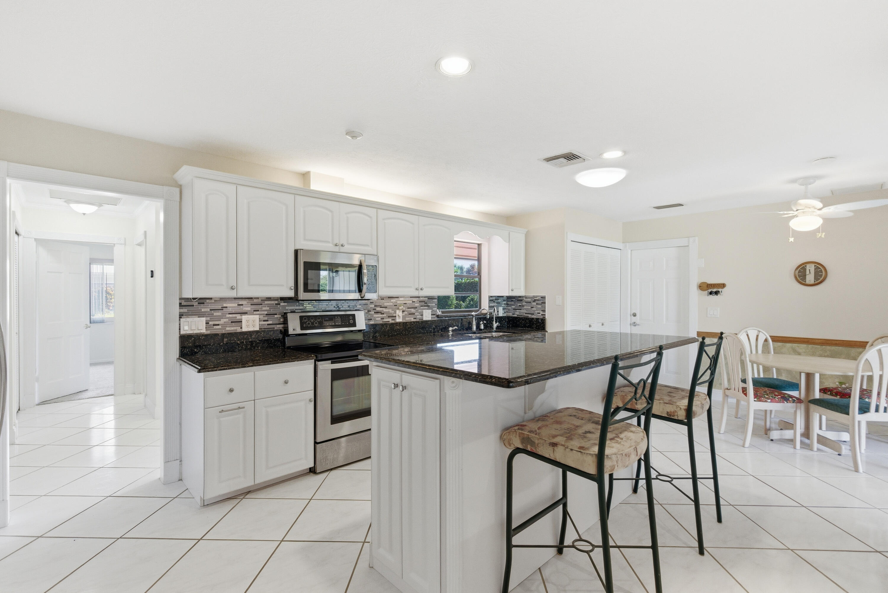5151 Southeast Burning Tree Circle Stuart, FL 34997 - Photo 8 of 74 a kitchen with white cabinets and chairs