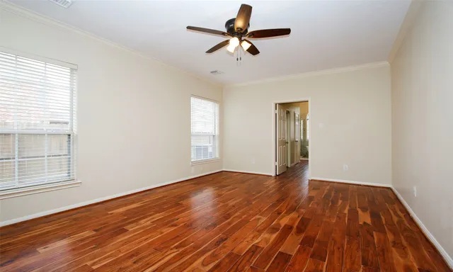 a view of empty room with wooden floor and fan