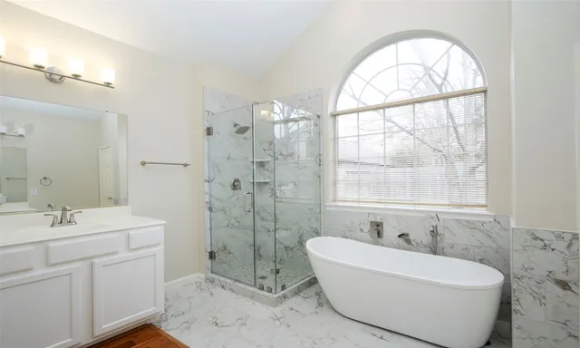 a bathroom with a sink bathtub and a large mirror