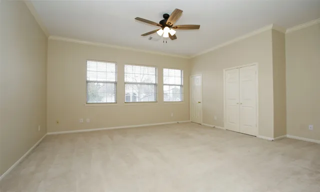 an empty room with chandelier fan and windows