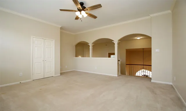 a view of an empty room with a windows and chandelier fan