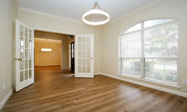 a view of an empty room with wooden floor and a window