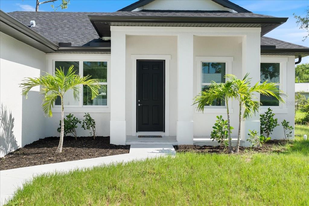 3299 Pinetree Street Port Charlotte, FL 33952 - Photo 1 of 6 a front view of a house with garden