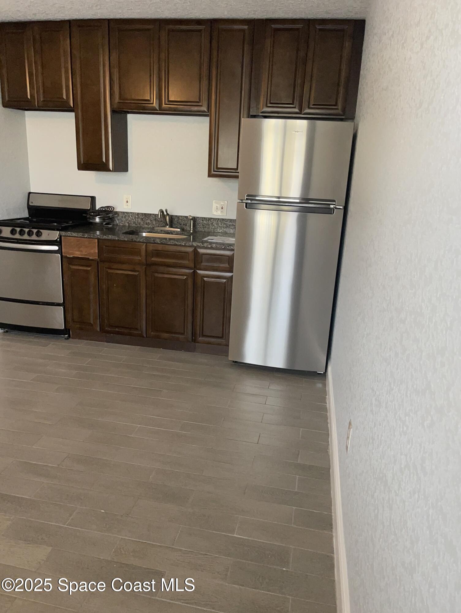 6100 Ridgewood Avenue, Unit 1 Cocoa Beach, FL 32931 - Photo 5 of 16 a kitchen with stainless steel appliances a refrigerator sink and cabinets