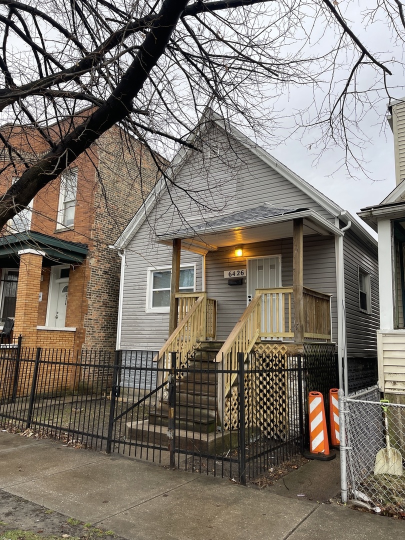 a view of a house with wooden fence and a large tree