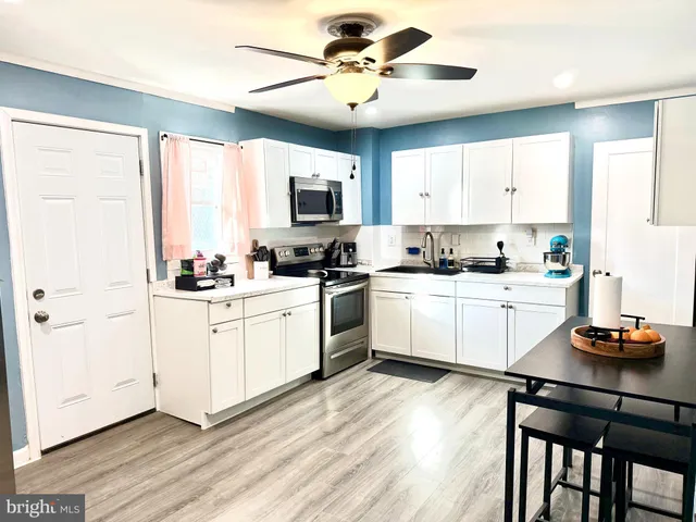 a kitchen with a sink white cabinets and white appliances
