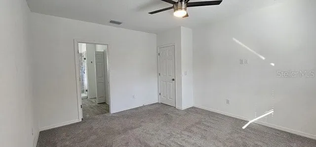 an empty room with a ceiling fan and mirror