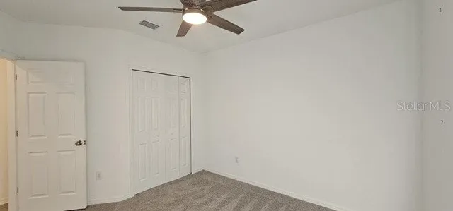 an empty room with a fan and a window