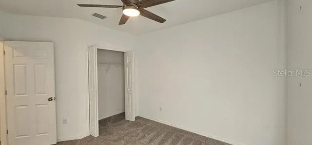 an empty room with a ceiling fan and carpet