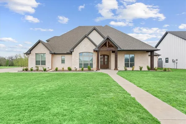 a view of a house with a big yard potted plants and large tree