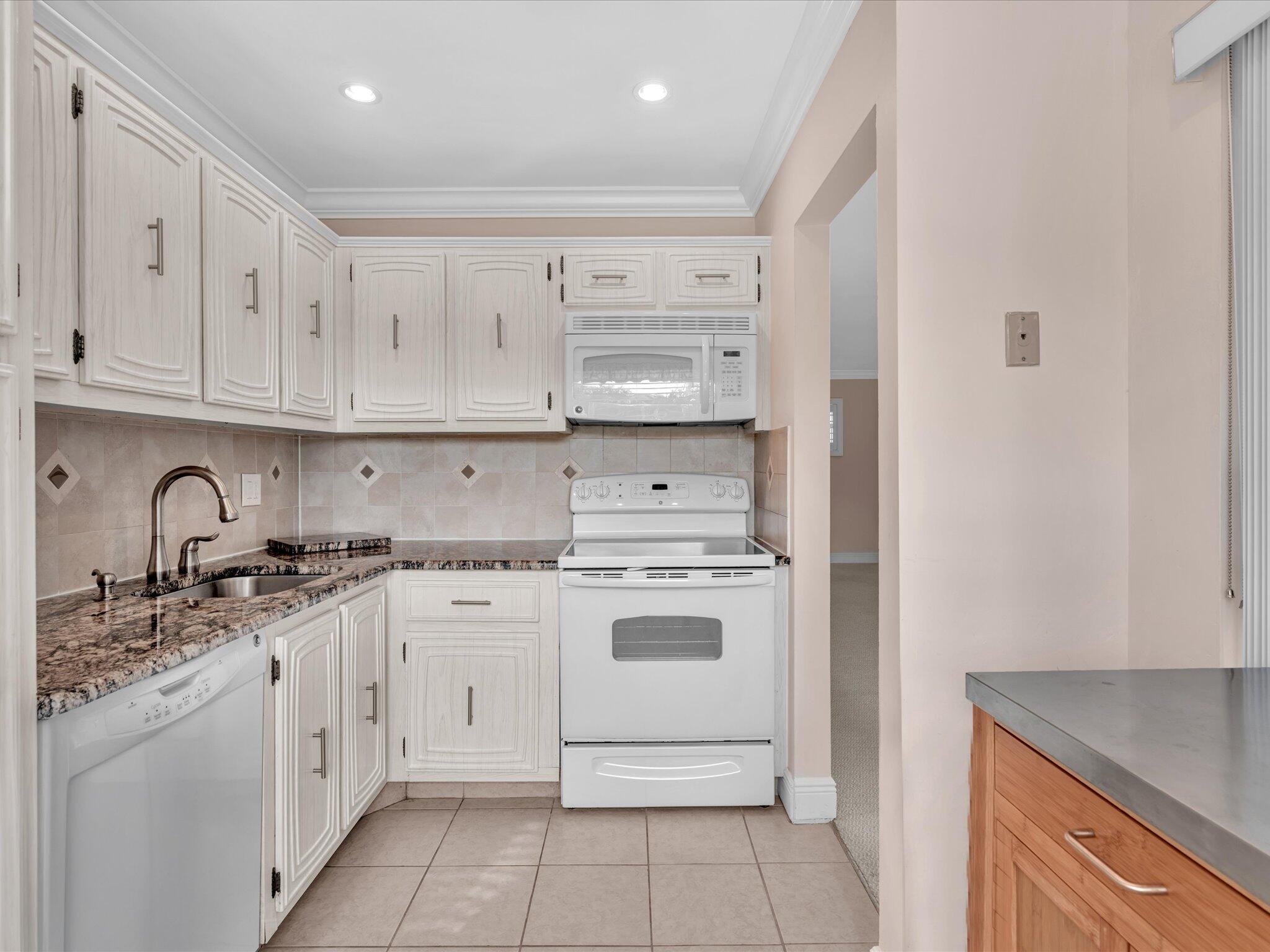 33 Colonial Club Drive, Unit 203 Boynton Beach, FL 33435 - Photo 14 of 61 a kitchen with granite countertop white cabinets and white appliances