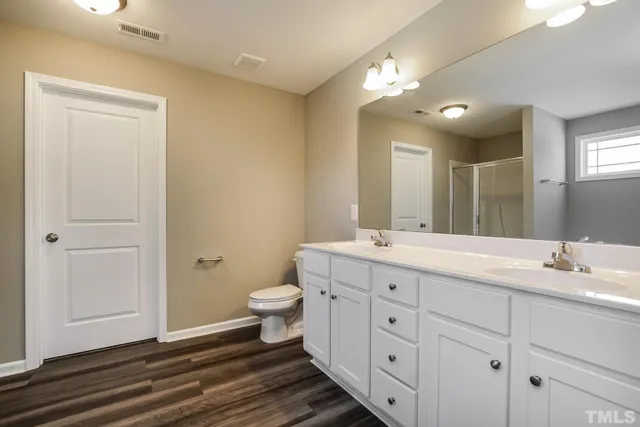 a spacious bathroom with a double vanity sink a toilet and a mirror