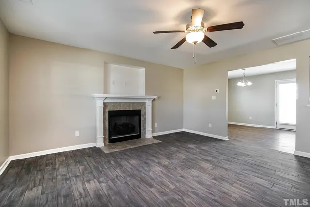 a view of an empty room with wooden floor fireplace and a window