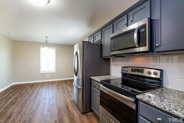 a kitchen with wooden floor and stainless steel appliances
