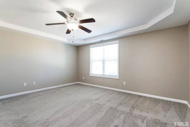 an empty room with ceiling fan and window