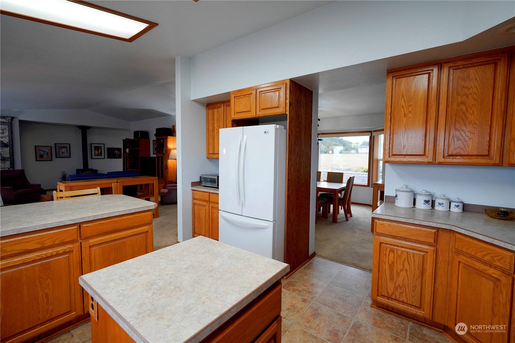 123 East Anderson Road Sequim, WA 98382 - Photo 14 of 40 a kitchen with a refrigerator a stove top oven a sink dishwasher and wooden cabinets with a dining table